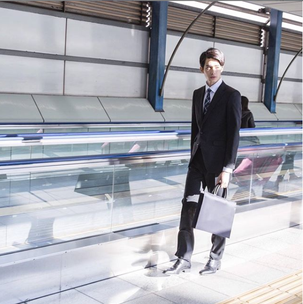 リクルートスーツスタイルの男性が、駅のホームを歩いている。