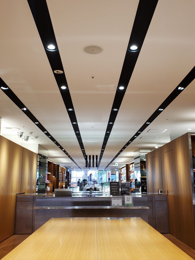 スーツセレクト店内画像。
横浜西店の中央のファンステージ。木目調の広い台の奥には、ブラウンで統一されたキャッシャー台。その奥は鏡張りになっている。
画像に alt 属性が指定されていません。ファイル名: 666%E2%98%85%E5%BA%97%E5%86%85%E5%86%99%E7%9C%9F%E2%91%A0-768x1024.jpg