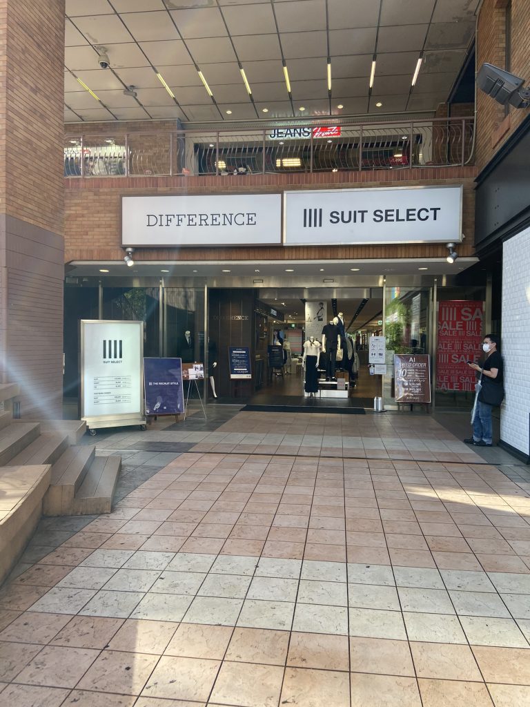 スーツセレクト横浜西の店頭画像。
店頭正面の画像。
ガラス張り、正面にマネキン人形2~3体が見える。difference、suit select両店の看板が入口上に掲げられている。看板はいずれも白地に黒。向かって左側にセレクトのつい立て看板あり。全体的に煉瓦調。